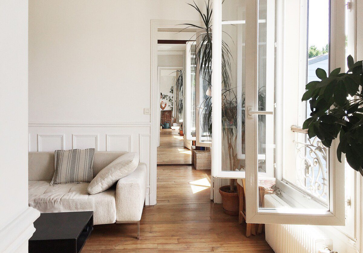 salon lumineux avec une fenêtre, un couloir et un canapé
